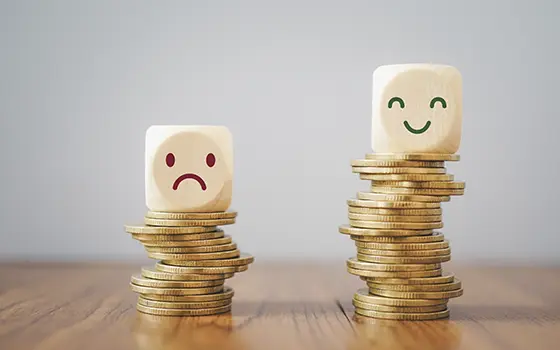 Two piles of money, the shorter with an unhappy face, the taller with a happy face