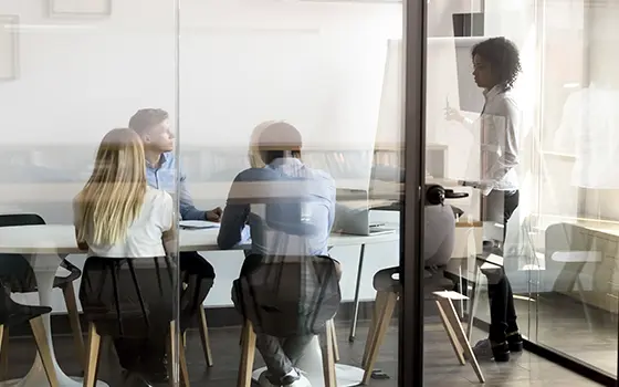 office workers having a meeting in a meeting room looking at a flipchart