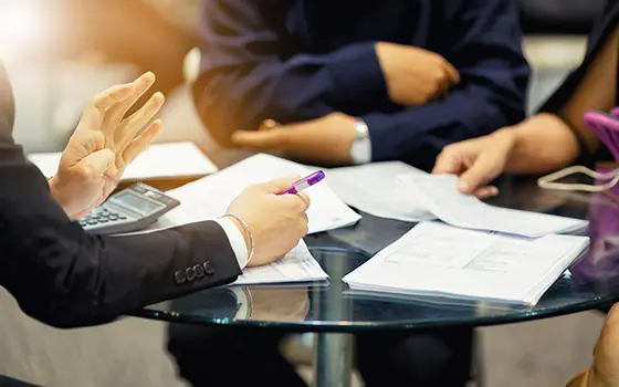 a business person discussing documents with two colleagues