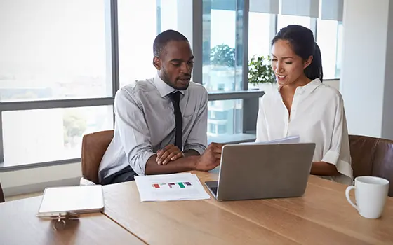 two colleagues having a meeting while looking at a laptop screen