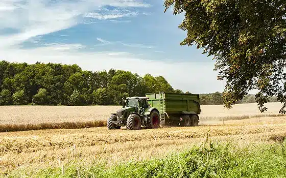 green tractor in a field harvesting its crop