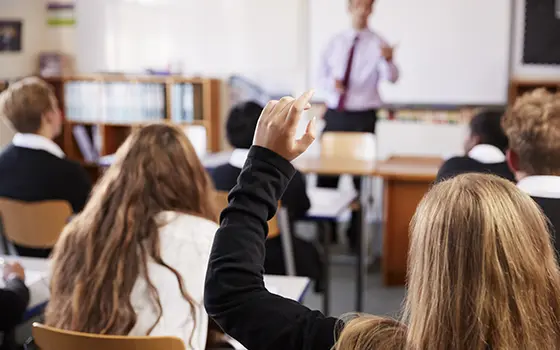 pupils raising her hand in a classroom