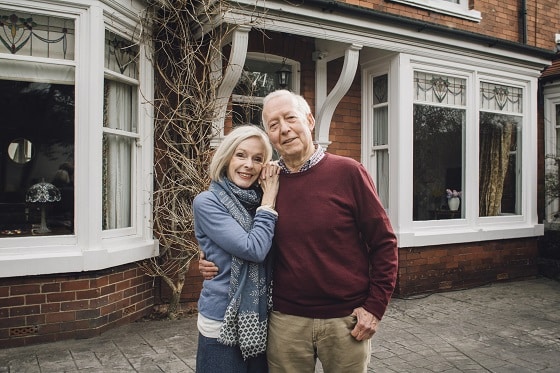 Happy Senior Couple standing outside of their house