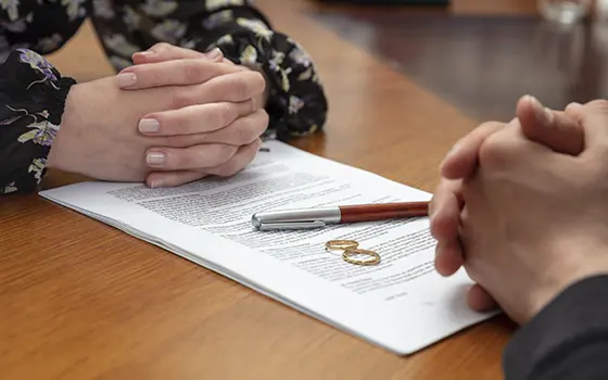 a man and a women signing a divorce document with their wedding rings off