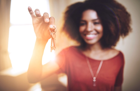 a smiling woman holding a set of keys up