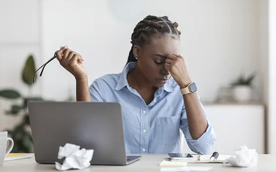 Overworked Female Entrepreneur Massaging Nosebridge At Workplace In Office