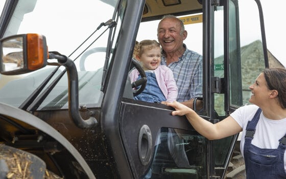 Grandfather and grandchild sitting inside a tractor smiling