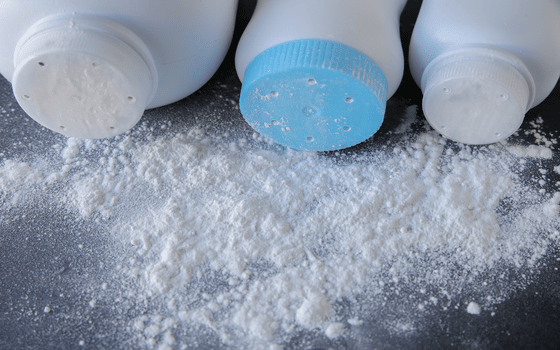 3 bottles of unbranded talc powder on side with powder on table