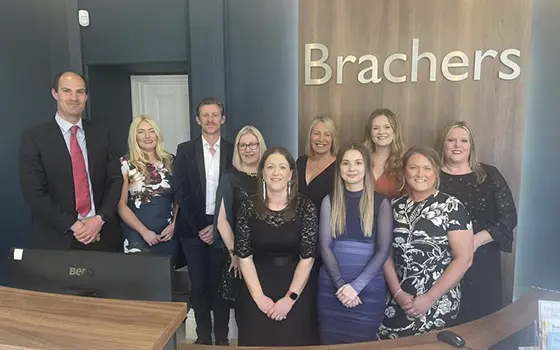 a group photo of the private client team at Brachers LLP, standing in the reception area with a Brachers sign in the background
